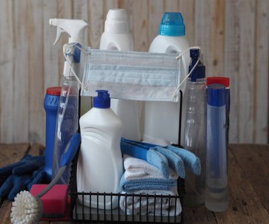 Dezenfeksiyon ve koronavirüs enfeksiyonuna karşı koruma. Ahşap bir arka planda temizlik maddesi dezenfektanının plastik şişelerindeki tıbbi maske. En iyi karantina seansı evi temizleyip dezenfekte etmektir..