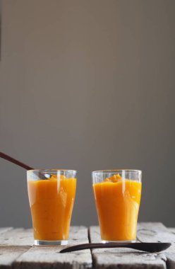 Balkabağının sağlık yararları. Balkabağı hamuru mikserden geçiyor. Evde yapılan doğal meyve püresi, ahşap bir masada ve gri arka planda..