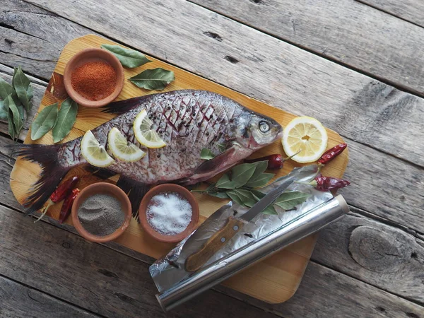 Çiğ nehir çipurası balığı, fırında limon dilimleri ve ahşap bir tahtanın üzerinde baharatla pişirmeye hazır. Üst görünüm, metin için yer.
