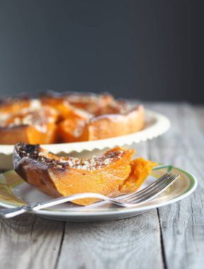 Şenlikli sonbahar balkabağı arkaplanı. Ahşap arka planda ceviz serpiştirilmiş fırında yuvarlak balkabağı tatlısı. Metin için yer.