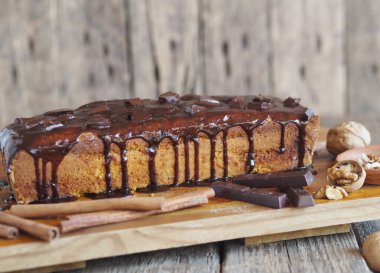 Mesaj için yer. Ev yapımı çikolatalı balkabağı uzun dikdörtgen kek, çikolatayla kaplı, mutfak tahtasının üzerinde yemeye hazır. Ahşap arkaplan.