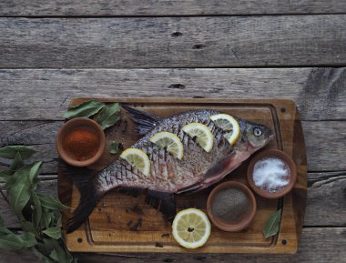 Yakın plan. Çiğ nehir balığı, fırında pişirmek için limon dilimleri ve ahşap bir tahtanın üzerinde baharat ile pişirilir. Yan görünüm, metin için yer