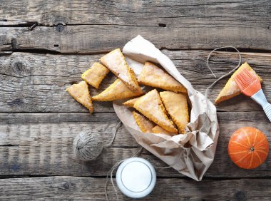 Ev yapımı ev yapımı jöleli çörekler, kabak kabaklı kurabiyeler, eski ahşap bir arka planda, kağıt ev ambalajında jöle olarak püsküllü. Yukarıdan görüntüle.