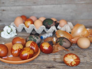 Paskalya için hazırlanıyorum. Yumurtaları bir ağla yapraklarla bağlayıp soğan kabuğunu doğal ahşap arka planda boyarız..