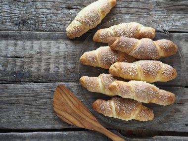 Eski bir ahşap zemine susam ve şeker serpiştirilmiş kruvasanlar. Ev yapımı kek..