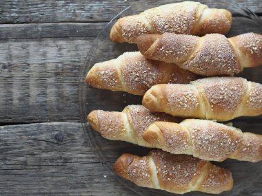 Eski bir ahşap zemine susam ve şeker serpiştirilmiş kruvasanlar. Ev yapımı kek..