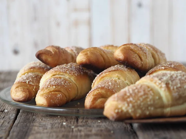 Croissants sprinkled with sesame and sugar on an ancient wooden background. Homemade cake.