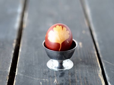 Yumurta standında soğan kabuğuyla boyanmış bir Paskalya yumurtası. Koyu tahta arkaplan.