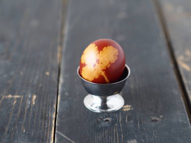Yumurta standında soğan kabuğuyla boyanmış bir Paskalya yumurtası. Koyu tahta arkaplan.