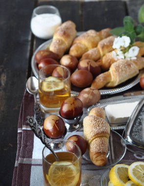 Paskalya arkaplanı yemek dolu bir masa. Paskalya yumurtaları, Paskalya pastasının arka planında limonlu çay. Koyu eski tahta masa..