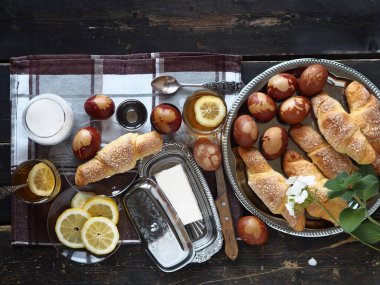 Paskalya arkaplanı ve yiyecek. Yukarıdan manzara. Paskalya yumurtaları, limon çayı, ahşap bir masada ev yapımı kekler..
