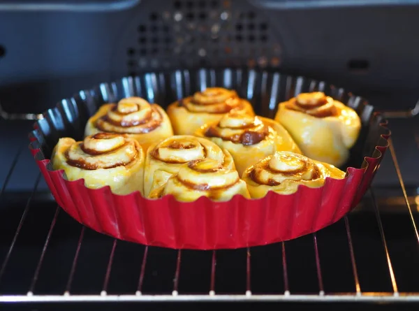 Home baking buns in a red form for baking in a home kitchen oven.