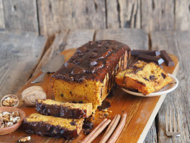 Mesaj için yer. Ev yapımı çikolatalı balkabağı uzun dikdörtgen kek, çikolatayla kaplı, mutfak tahtasının üzerinde yemeye hazır. Ahşap arkaplan.