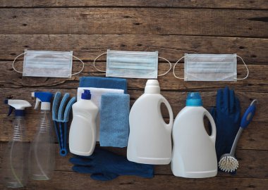 Coronavirus 2020. Karantina sırasında evi temizleme fikri. Tahta zeminde temizlik ürünleri olan tıbbi koruyucu maske. Evde kal ve dezenfekte et..