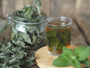 Kurutulmuş Melissa kullanarak şifalı bitki çayı. Melissa 'nın kurumuş yaprakları ya da eski ahşap bir masadaki bardakta taze bir dal ve tütsülenmiş nane şekeri..
