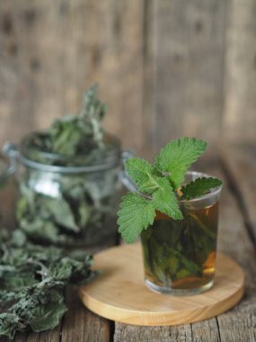 Kurutulmuş Melissa kullanarak şifalı bitki çayı. Melissa 'nın kurumuş yaprakları ya da eski ahşap bir masadaki bardakta taze bir dal ve tütsülenmiş nane şekeri..