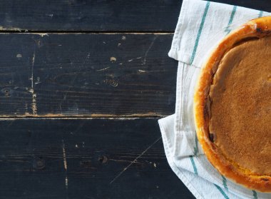 Ev yemeği. Turuncu kabaklı turta. Koyu ahşap arka planda doğal vejetaryen tatlısı. Üst görünüm, düz biçim.