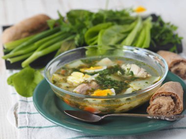 Sağlıklı yiyecek. Bir kase yeşil talaş çorbası. Beyaz ahşap bir masada yeşil malzemelerle dolu bir ekmek..