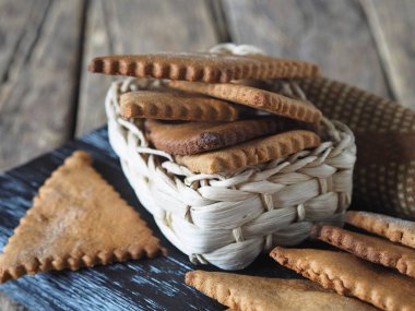 Yukarıdan manzara. Sağlıklı doğal tatlı hakkında bir geçmiş. İçinde ev yapımı çavdar unu diyet kurabiyeleri olan hasır sepet. Eski bir ahşap masanın üzerinde, karanlık bir mutfak tahtasında..