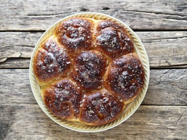 Yukarının manzarasını kapat. Ev yapımı çörekler reçel dolgulu, susam ve krema serpiştirilmiş eski bir ahşap arka planda.
