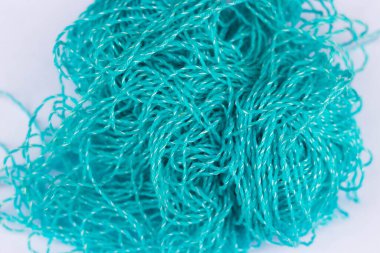 Örgü temasının arka planı. Beyaz bir zemin üzerinde karmakarışık mavi akrilik iplik topu. Merkezde odaklanma ve kenarlarda bulanıklaşma.