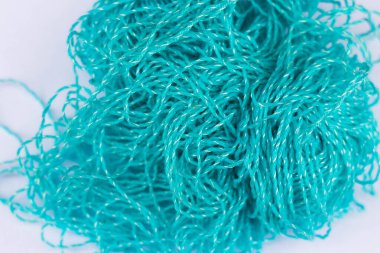 Örgü temasının arka planı. Beyaz bir zemin üzerinde karmakarışık mavi akrilik iplik topu. Merkezde odaklanma ve kenarlarda bulanıklaşma.