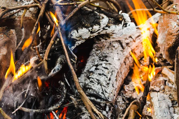 Burning wood (fire, coals and smoke). Lighting a fire from wooden logs and branches in a homemade barbecue made of bricks for cooking barbecue close up