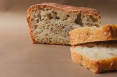 Ev yapımı çavdar ekmeği mayasız ekmek ve canlı ekşi ekmek. İki dilim çavdar ekmeği, bej keten kumaşın üzerinde yakın plan çekimde kalan ekmeği de arka planda yumuşak odaklı.