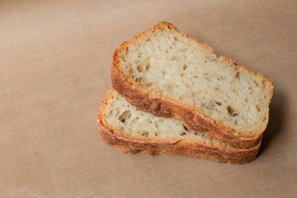 Homemade rye-wheat yeast-free bread made from live sourdough. Two slices of rye-wheat bread with flax and sunflower seeds close-up on a beige linen tablecloth from Kopi space