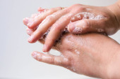 Higiénia és a kezek védelme a vírusok (koronavírus) és baktériumok ellen szappannal. Női kezek habosított szappannal, közelkép fehér háttérrel. A megfelelő kézmosás szappannal.