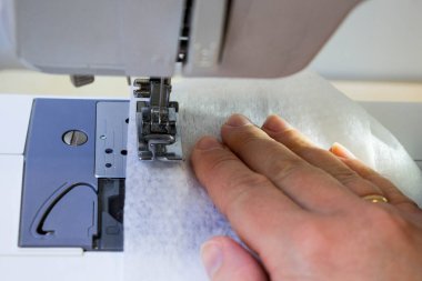 Evde dikiş makinesine dikiş dikiyorum. Koronavirüs salgını sırasında korunması ve önlenmesi gerekenler için dikiş ekipmanlarının üretimi ve dikimi