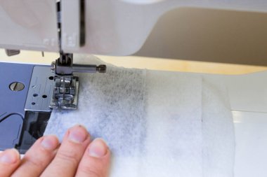 Evde dikiş makinesine dikiş dikiyorum. Koronavirüsten korunması ve korunması gereken kişiler için maske üretimi ve dikiş ekipmanları Maske sıkıntısı çekenlere karşı