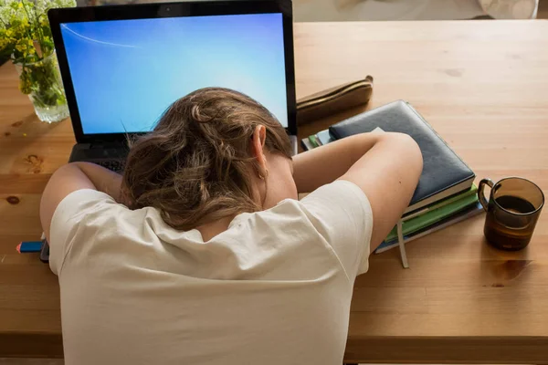 Distance learning and computer work during the coronavirus pandemic. A student who fell asleep in front of a laptop during distance learning during a quarantine close-up from the upper back.