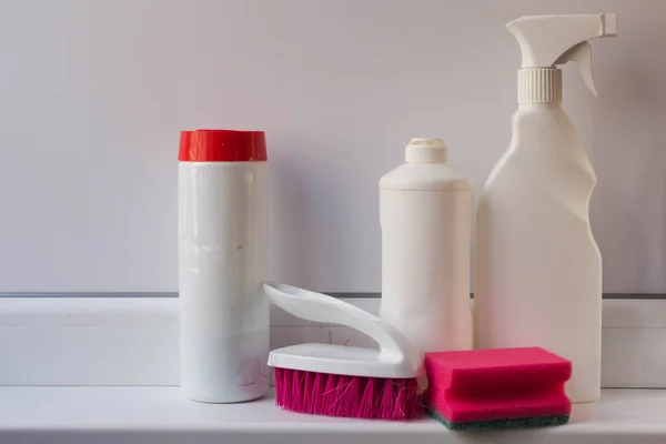 Tools for cleaning the house. Cleaning gel, powder and spray for cleaning and disinfecting various surfaces in plastic white containers with a pink brush  and  sponge on a white background.