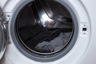 Çamaşır makinesinde yıkanmak. Çamaşır makinesinin fıçısını siyah ve gri pamuklu giysilerle yakın çekim için hazırlayın.