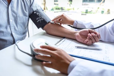 Doktor steteskop kullanarak arteryel kan basıncını ölçüyor.