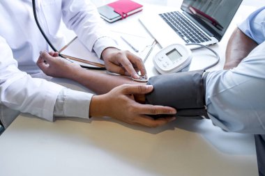 Doktor steteskop kullanarak arteryel kan basıncını ölçüyor.
