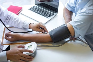 Doktor steteskop kullanarak arteryel kan basıncını ölçüyor.