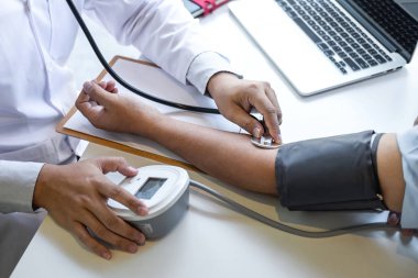 Doktor steteskop kullanarak arteryel kan basıncını ölçüyor.