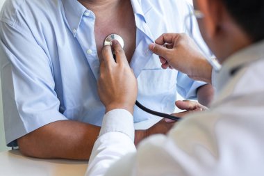 Doktor steteskop kullanarak kalp atışlarını ölçüyor.