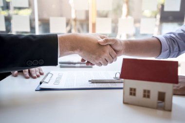 Emlakçı iyi bir anlaşma yaptıktan sonra el sıkışıyor.