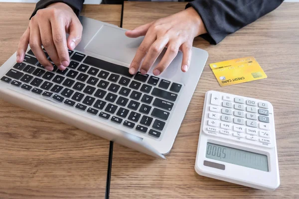 Businesswoman using laptop and holding credit card for paying de