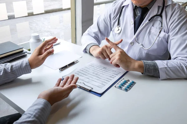 Doctor presenting with patient and checking results on report an — Stock Photo, Image