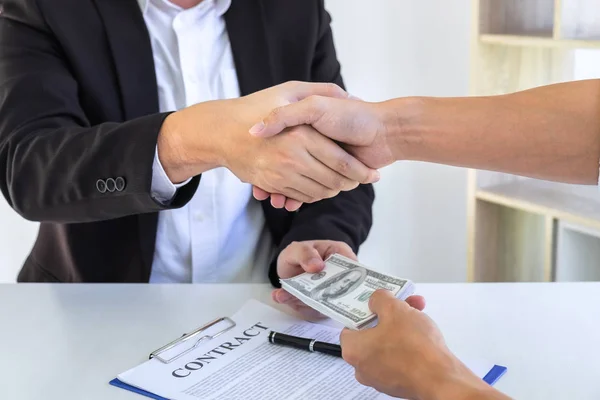 Businessman handshake with money of dollar banknotes in hands fr