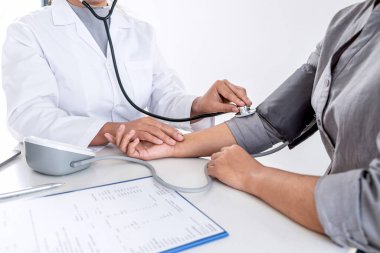 Doktor steteskop kullanarak arteryel kan basıncını ölçüyor.