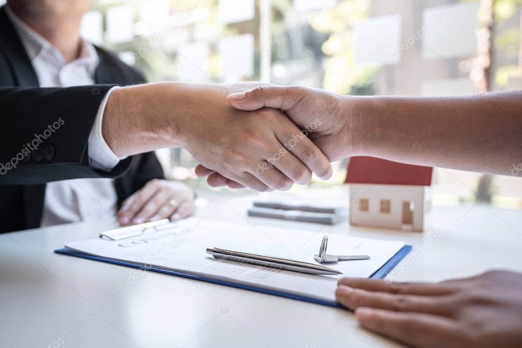 Real estate agent are shaking hands after good deal and giving h