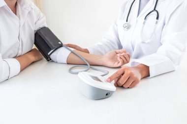 Kan basıncı monitörü ve steteskop kullanan doktor kolundaki kan basıncını ölçmek için hastanedeki bir hastaya, sağlık hizmetlerine ve tıbbi konsepte bakıyor..