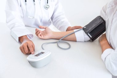 Kan basıncı monitörü ve steteskop kullanan doktor kolundaki kan basıncını ölçmek için hastanedeki bir hastaya, sağlık hizmetlerine ve tıbbi konsepte bakıyor..