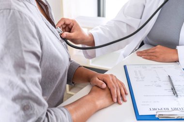 Doktor steteskop kullanarak hastayı hastalık, hastalık durumları ve tedavi yöntemleri hakkında kontrol ediyor..