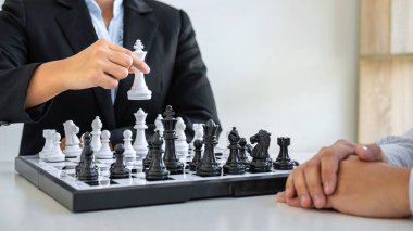 Oyuncularla, iş adamlarıyla ve iş kadınlarıyla, rakip oyuncularla rekabet içinde satranç figürlerini hareket ettirmeye yönelik strateji düşünen ve kazanmak için oynamayı planlayan siyah-beyaz satranç.